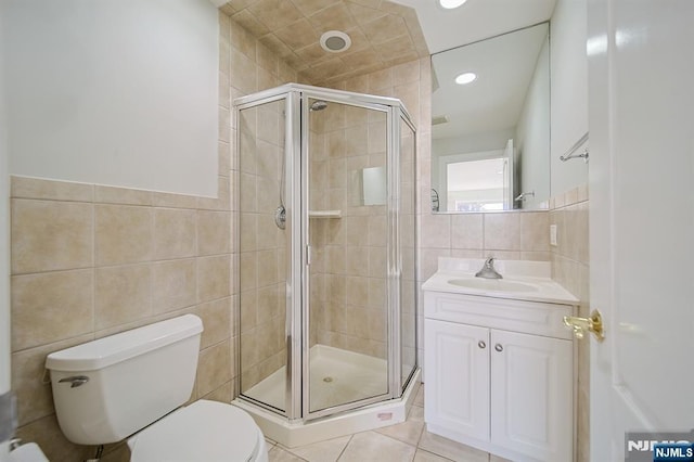 full bath with tile patterned floors, toilet, a stall shower, tile walls, and vanity