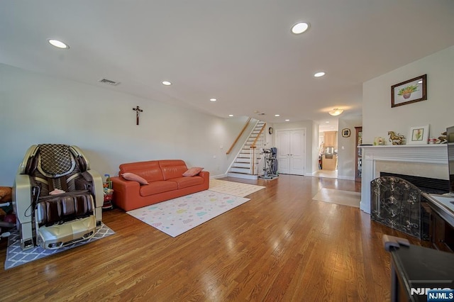 living area with visible vents, recessed lighting, stairs, and wood finished floors