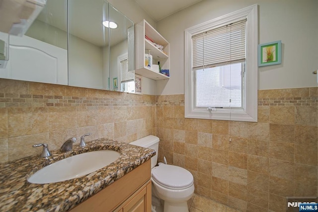 bathroom with vanity, tile walls, toilet, and wainscoting