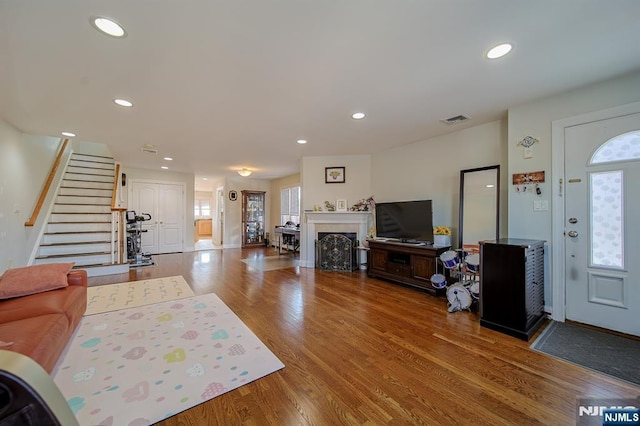 living room featuring visible vents, wood finished floors, recessed lighting, a fireplace, and stairs