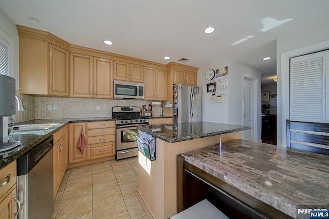 kitchen with visible vents, backsplash, dark stone countertops, stainless steel appliances, and a sink