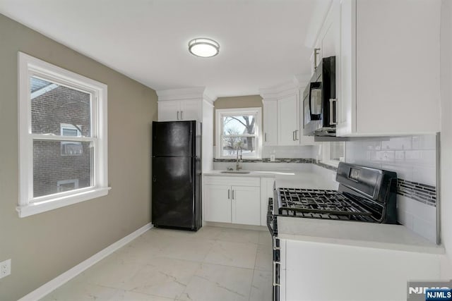 kitchen with baseboards, decorative backsplash, marble finish floor, black appliances, and a sink