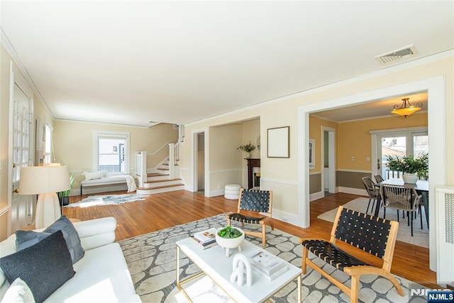 living room featuring stairway, wood finished floors, visible vents, and a wealth of natural light