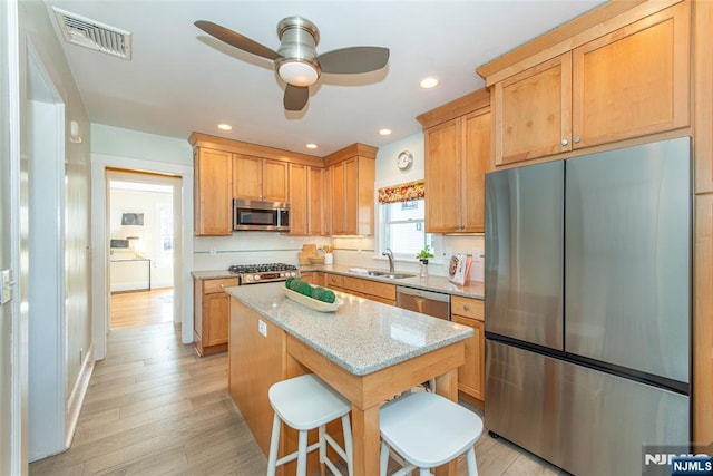 kitchen with visible vents, ceiling fan, light stone counters, appliances with stainless steel finishes, and a sink