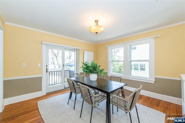 dining space with crown molding, baseboards, and light wood-type flooring