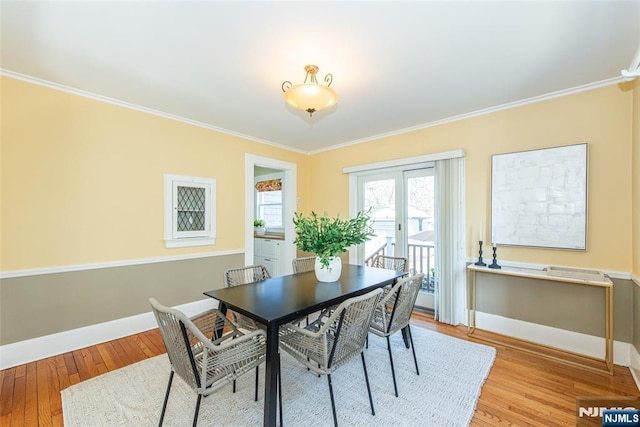 dining space featuring baseboards, wood finished floors, and crown molding