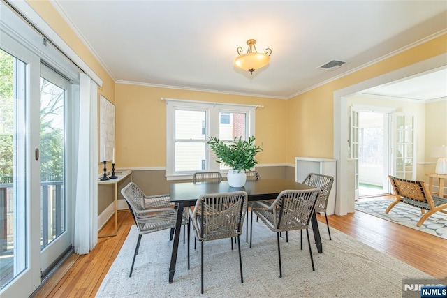 dining room featuring a wealth of natural light, visible vents, ornamental molding, and wood finished floors