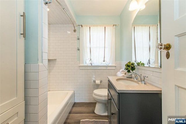 full bathroom featuring vanity, wood finished floors, wainscoting, tile walls, and toilet