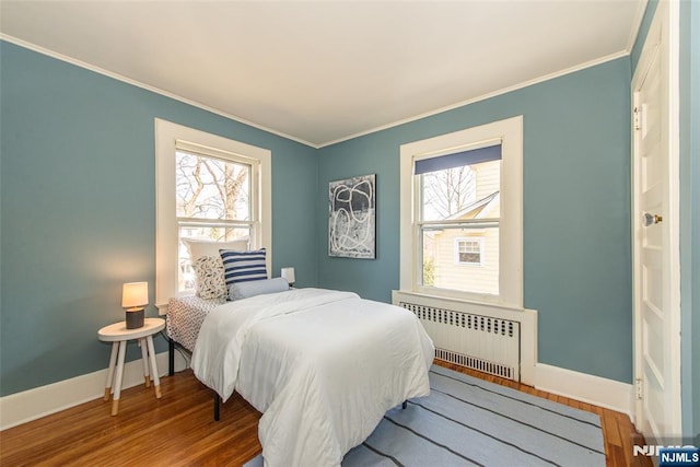 bedroom featuring multiple windows, wood finished floors, and radiator heating unit