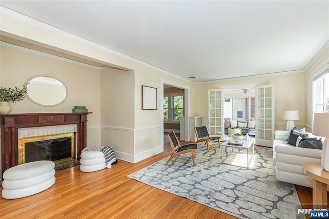 living area with plenty of natural light, wood finished floors, and ornamental molding