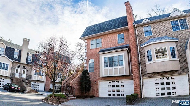 townhome / multi-family property featuring brick siding, an attached garage, and driveway