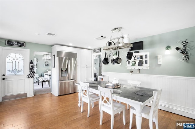 dining area featuring visible vents, a wainscoted wall, and light wood finished floors