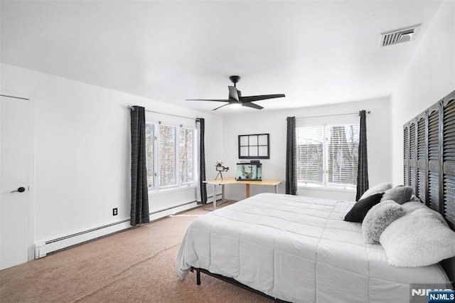 carpeted bedroom with visible vents, multiple windows, a baseboard heating unit, and a ceiling fan