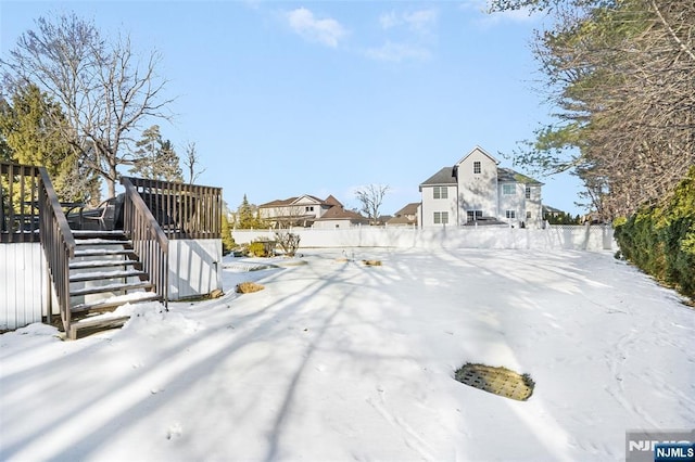 yard covered in snow featuring stairs, a deck, and fence