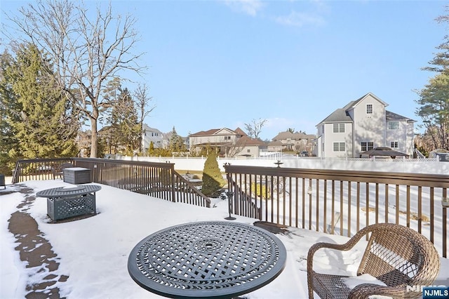 snow covered patio with a residential view, a deck, and fence