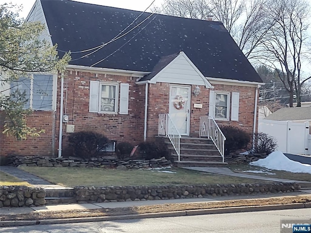 view of front of house featuring brick siding and fence