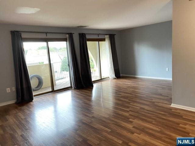 unfurnished room with dark wood-style floors and baseboards