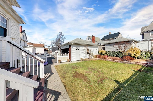 view of yard featuring an outbuilding, a residential view, and fence