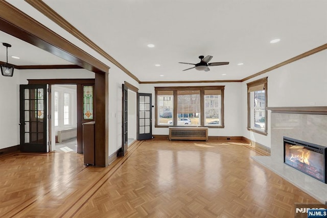 unfurnished living room with baseboards, a healthy amount of sunlight, ceiling fan, and radiator heating unit