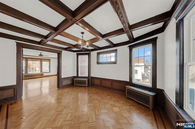 spare room featuring a wainscoted wall, beam ceiling, coffered ceiling, and an inviting chandelier