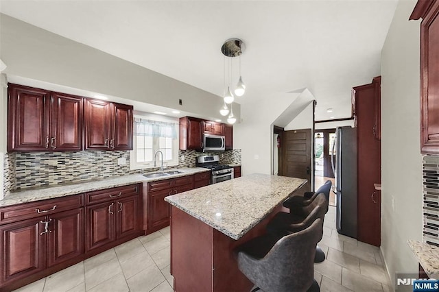 kitchen featuring a sink, tasteful backsplash, a kitchen island, appliances with stainless steel finishes, and dark brown cabinets