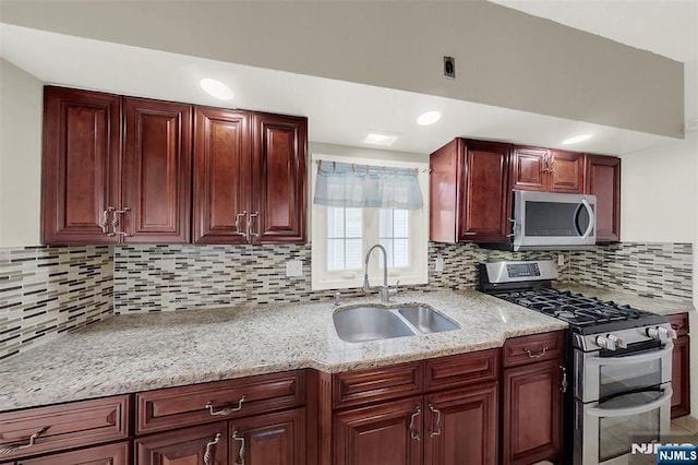 kitchen with light stone counters, tasteful backsplash, appliances with stainless steel finishes, and a sink