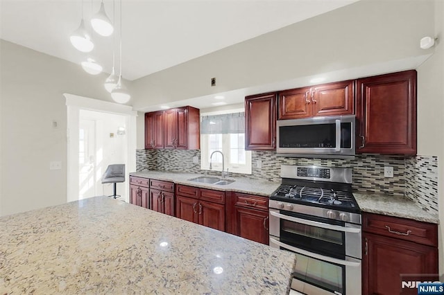 kitchen featuring a sink, hanging light fixtures, stainless steel appliances, dark brown cabinets, and tasteful backsplash