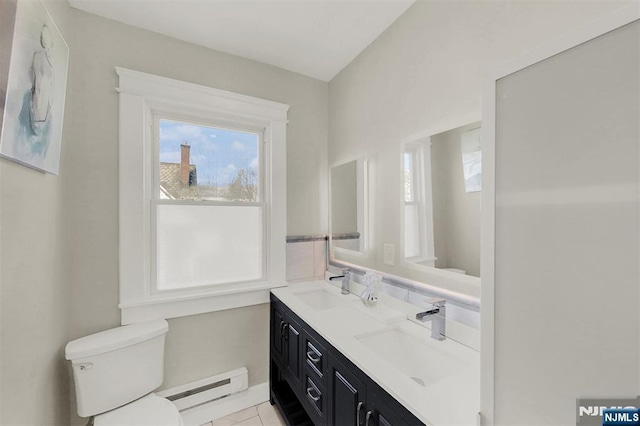 bathroom featuring a sink, a baseboard heating unit, toilet, and double vanity