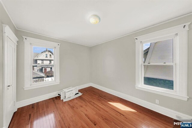 spare room featuring baseboards, hardwood / wood-style floors, and crown molding