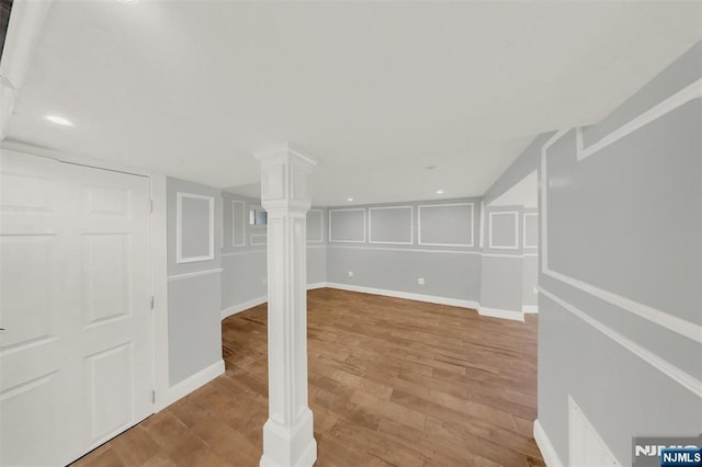 finished basement featuring a decorative wall, recessed lighting, light wood-type flooring, and baseboards