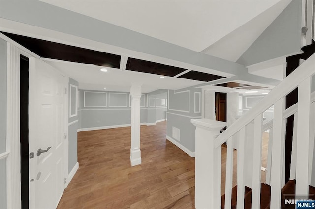 finished basement with stairway, baseboards, recessed lighting, a decorative wall, and light wood-type flooring