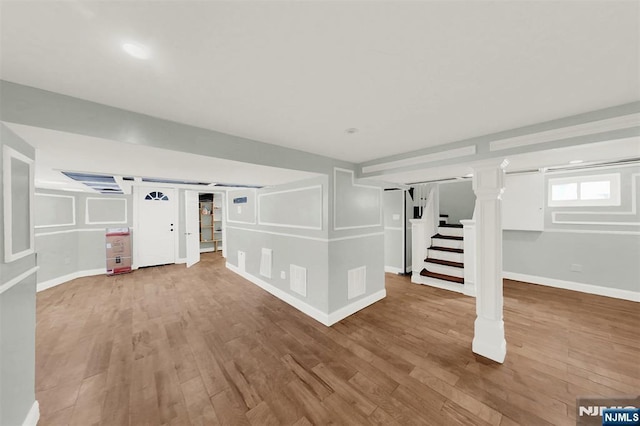 below grade area with stairs, wood finished floors, visible vents, and baseboards