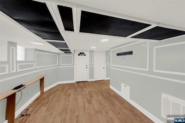 below grade area with wood finished floors, visible vents, and baseboards