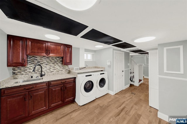 washroom with washing machine and dryer, light wood-style flooring, baseboards, and a sink