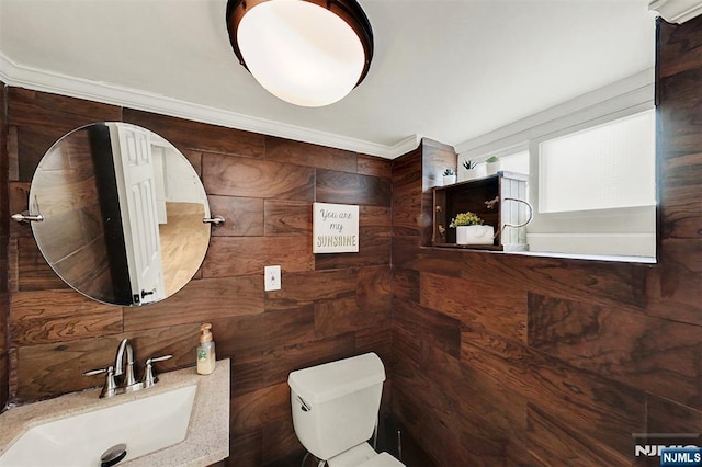 half bath with a sink, backsplash, toilet, and ornamental molding