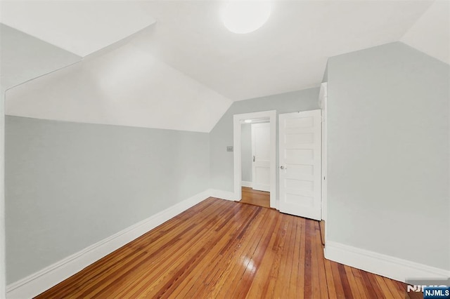 bonus room with hardwood / wood-style floors, baseboards, and vaulted ceiling