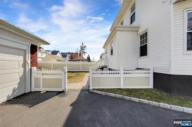 view of side of property featuring aphalt driveway and fence