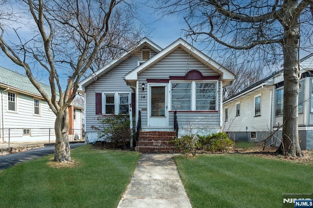 bungalow-style home with entry steps and a front lawn