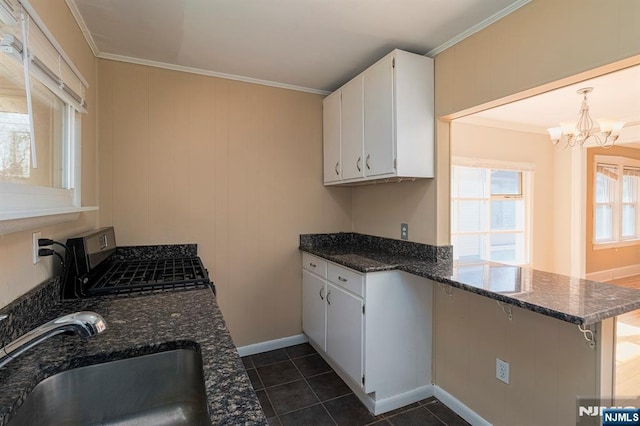 kitchen with ornamental molding, range with gas stovetop, a peninsula, a notable chandelier, and a sink