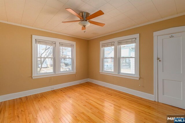 empty room featuring a ceiling fan, crown molding, light wood-style floors, and baseboards