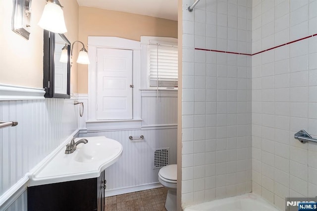 bathroom featuring a wainscoted wall, toilet, vanity, and visible vents