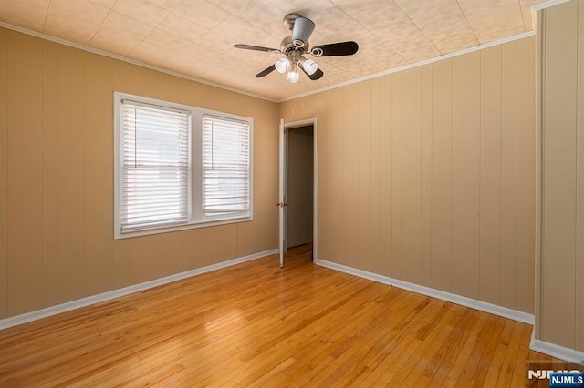 empty room featuring ceiling fan, baseboards, crown molding, and light wood-style floors