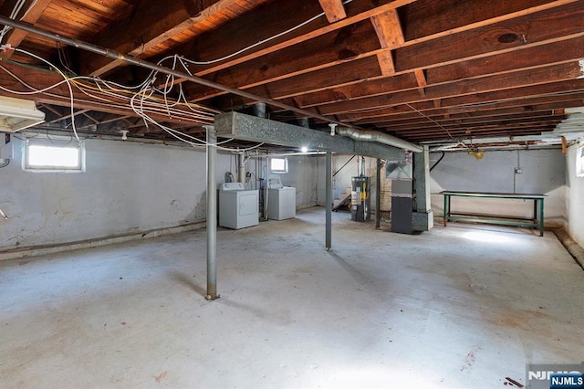 basement featuring washer and dryer, heating unit, and water heater