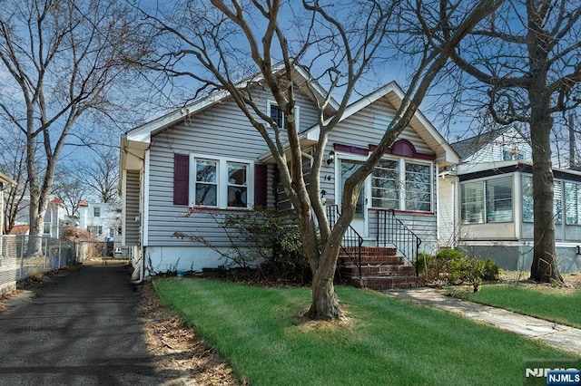 bungalow with a front lawn and fence