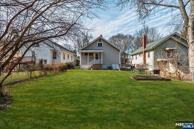 back of house featuring a garden, fence, and a lawn