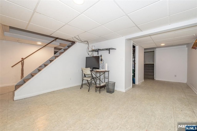 finished below grade area with tile patterned floors, baseboards, a paneled ceiling, and stairs