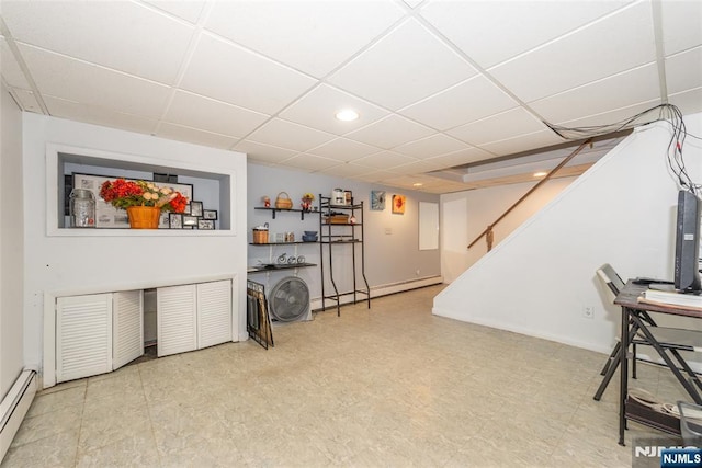 finished below grade area with tile patterned floors, a drop ceiling, baseboard heating, and stairway