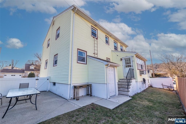 back of house featuring a patio area, a yard, a fenced backyard, and a gate