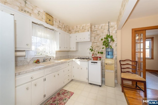 kitchen featuring light floors, light countertops, white dishwasher, white cabinetry, and a sink