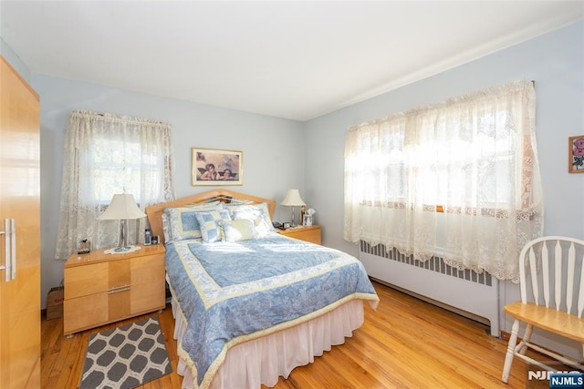 bedroom with radiator heating unit and wood finished floors